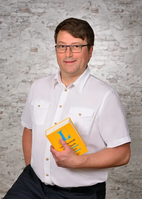 Jürgen Prelitsch mit einem Langenscheid Lexikon in der Hand klicken zum vergrößern